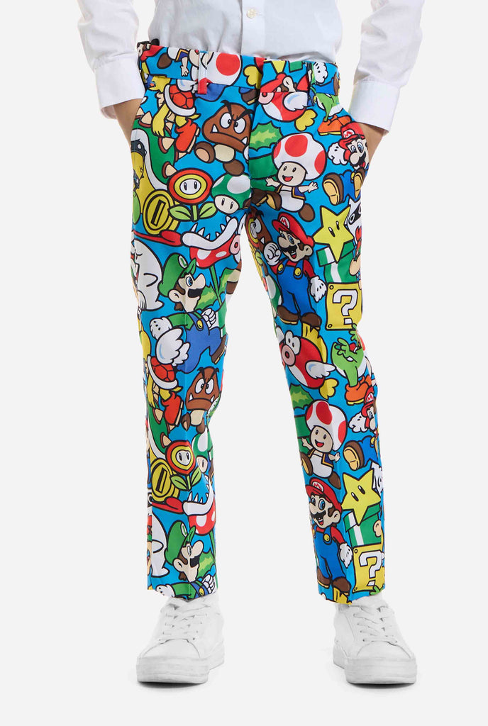 Bild eines Kindes, das einen Anzug mit Super Mario-Allover-Print trägt, bestehend aus Blazer, Hose und Krawatte. Die Hauptfarbe ist blau, aber es gibt auch gelb, rot und weiß.