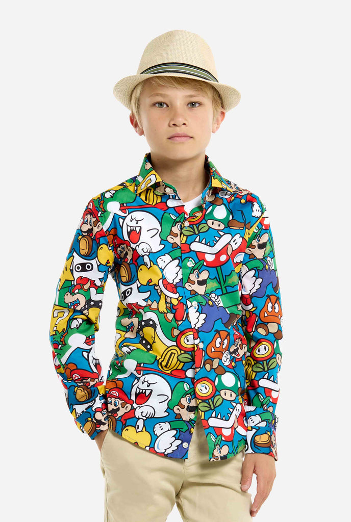 Bild eines Teenagers, der ein T-Shirt mit Super Mario-Allover-Print trägt. Die Hauptfarbe ist Blau, aber es gibt auch Gelb, Rot und Weiß.