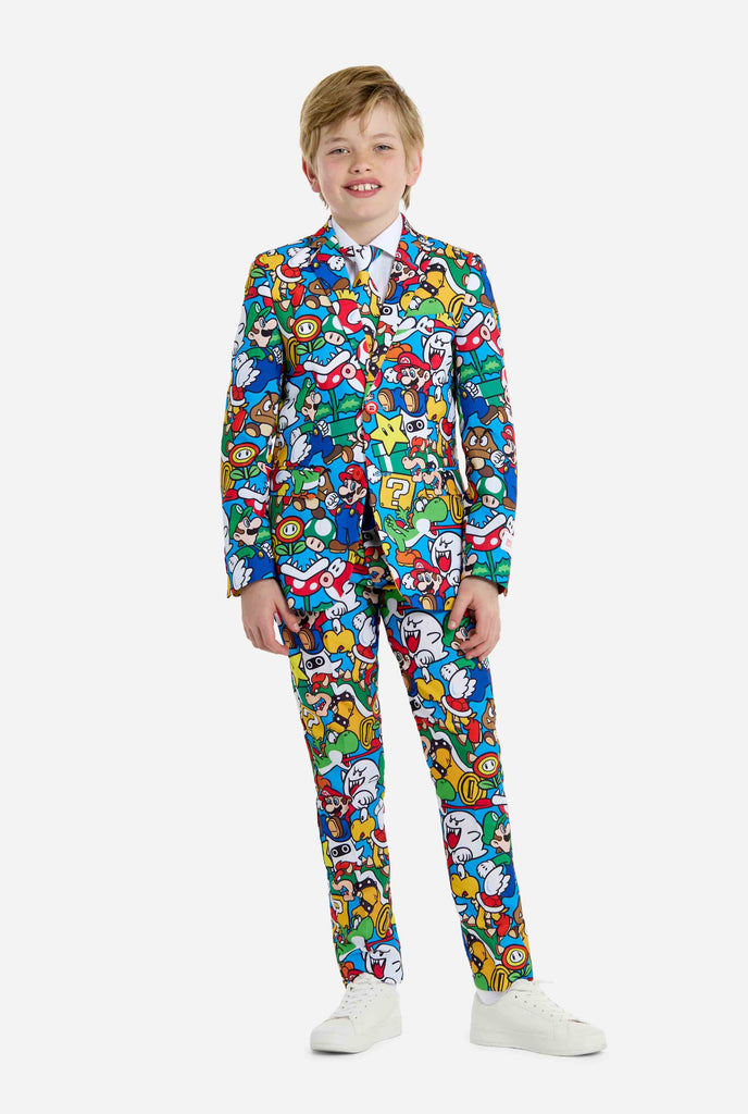 Bild eines Teenagers, der ein Hemd mit Super Mario-Allover-Print trägt, bestehend aus Blazer, Hose und Krawatte. Die Hauptfarbe ist blau, aber es gibt auch gelb, rot und weiß.