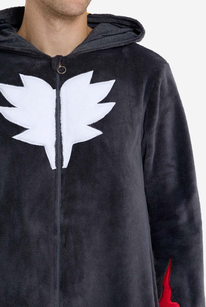 Ein Mann trägt einen plüschigen schwarzen Onesie, der von der beliebten Igelfigur Shadow inspiriert ist, mit stacheligen roten und schwarzen Akzenten auf der Kapuze, einem weißen Brustemblem und gelben Handgelenkdetails. Der Onesie ist aus weichem Fleecematerial gefertigt und bietet Komfort und ein verspieltes Design für Cosplay, Relaxen oder Themenveranstaltungen.