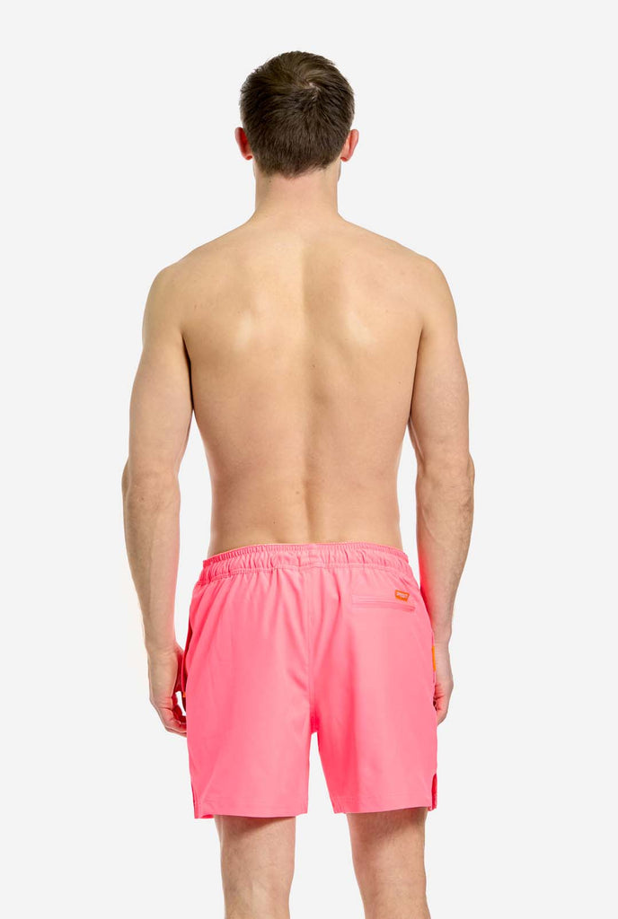 Man wearing Neon Pink Power swim trunks for men, view from the back