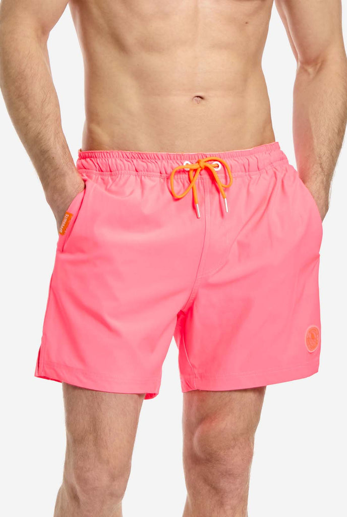 Man wearing Neon Pink Power swim trunks for men, close up