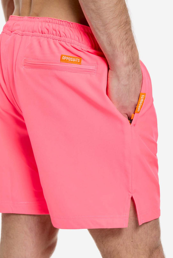 Man wearing Neon Pink Power swim trunks for men, close up