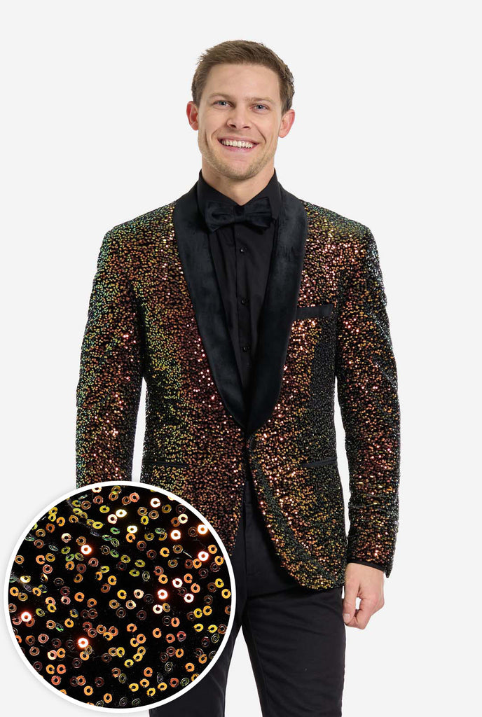 Mann trägt einen Blazer, der mit schimmernden bernsteinfarbenen Pailletten bedeckt ist, die das Licht in verschiedenen Gold-, Kupfer- und Grüntönen reflektieren. Inclusive close up.