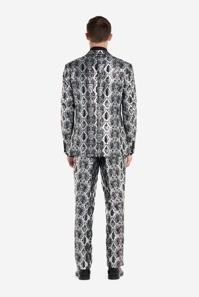 Ein Mann trägt einen auffälligen silber-schwarzen Anzug mit Schlangenmuster von OppoSuits. Der auffällige Anzug weist ein auffälliges Schlangenhautmuster auf und bietet einen eleganten, modischen Look, der sich perfekt für Partys, Veranstaltungen oder ein gewagtes Modestatement eignet. Der Herrenanzug wird mit einem schwarzen Oberhemd und einer passenden Krawatte mit Schlangenmuster kombiniert, was dem Gesamtensemble eine raffinierte Note verleiht.