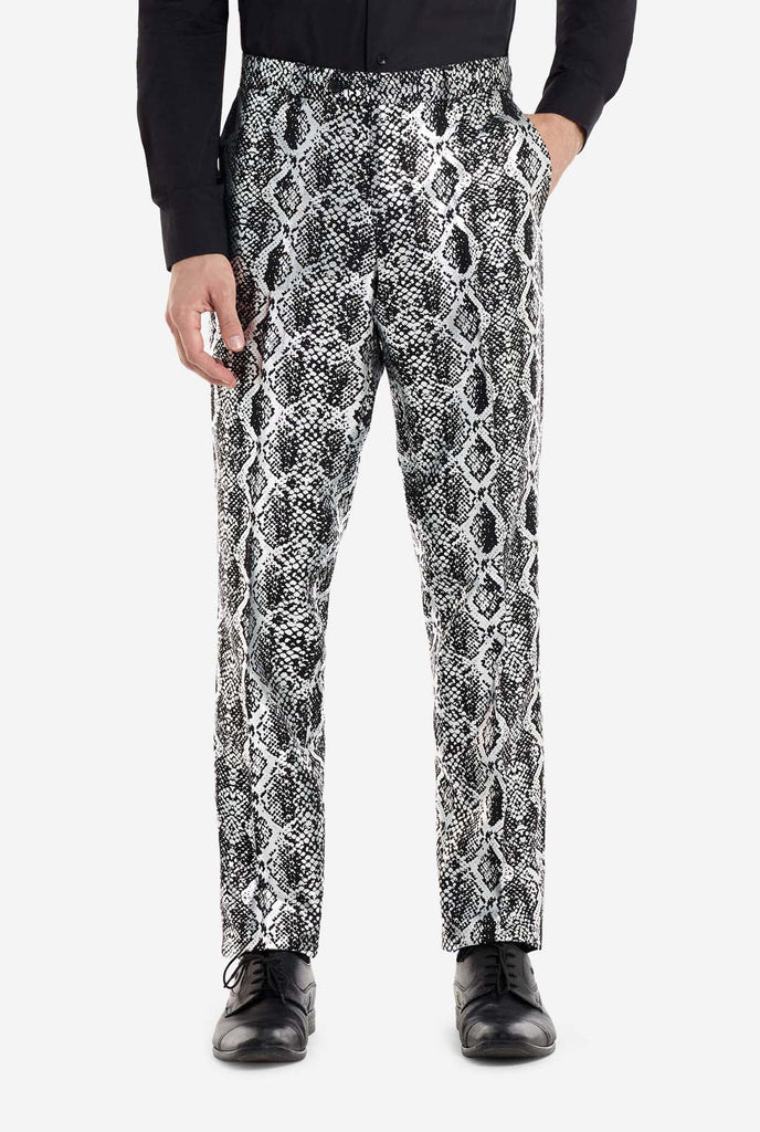 Ein Mann trägt einen auffälligen silber-schwarzen Anzug mit Schlangenmuster von OppoSuits. Der auffällige Anzug weist ein auffälliges Schlangenhautmuster auf und bietet einen eleganten, modischen Look, der sich perfekt für Partys, Veranstaltungen oder ein gewagtes Modestatement eignet. Der Herrenanzug wird mit einem schwarzen Oberhemd und einer passenden Krawatte mit Schlangenmuster kombiniert, was dem Gesamtensemble eine raffinierte Note verleiht.