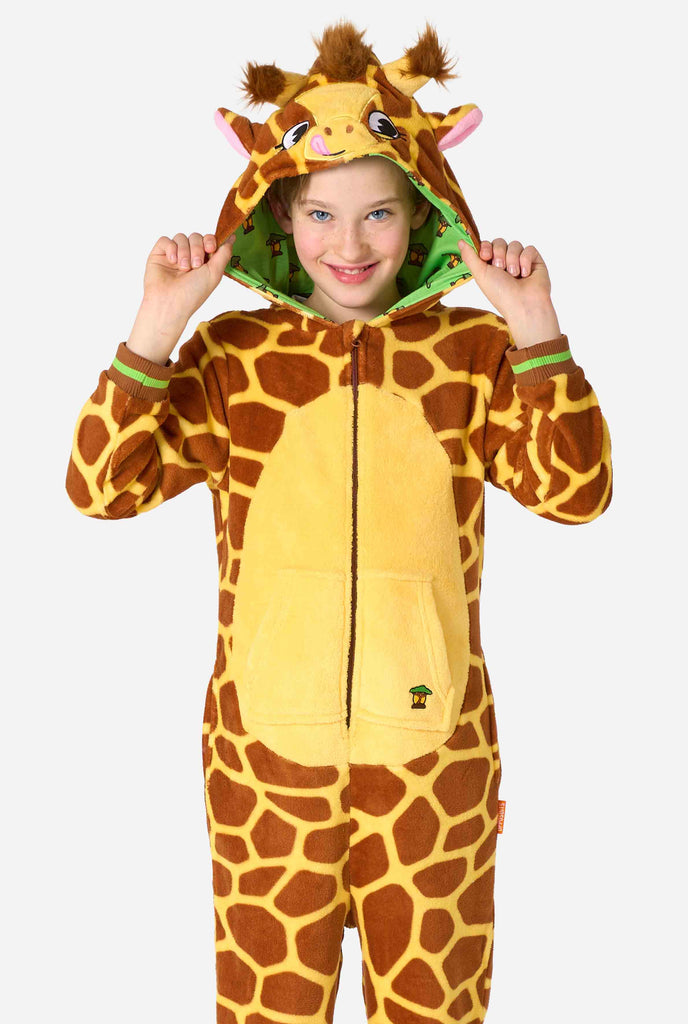 Ein lächelndes Kind trägt einen braun-gelben Kinder Onesie in Form einer Giraffe. Der Onesie hat eine Kapuze, die an den Kopf einer Giraffe erinnert.