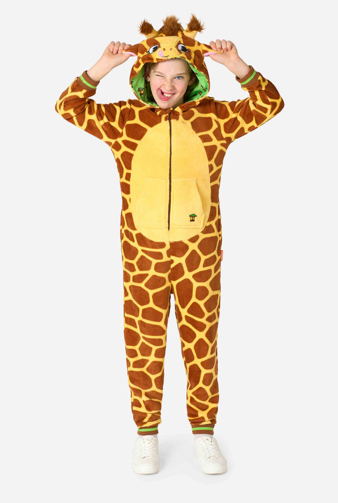 Ein lächelndes Kind trägt einen braun-gelben Kinder Onesie in Form einer Giraffe. Der Onesie hat eine Kapuze, die an den Kopf einer Giraffe erinnert.