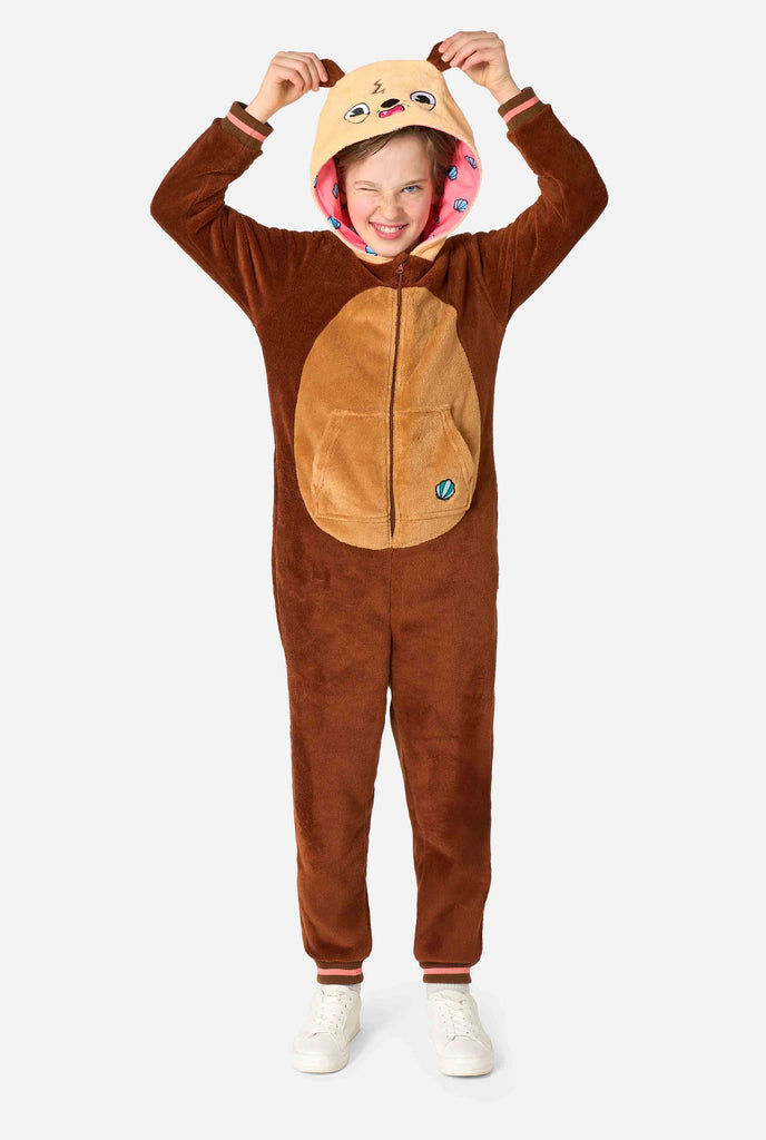 A smiling kid is wearing a brown kids onesie designed as an otter. The onesie features a hood with ears, a cute face, and playful otter details. Full body image.