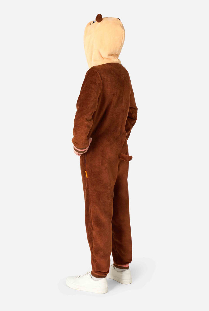 A smiling kid is wearing a brown kids onesie designed as an otter. The onesie features a hood with ears, a cute face, and playful otter details. Side view.