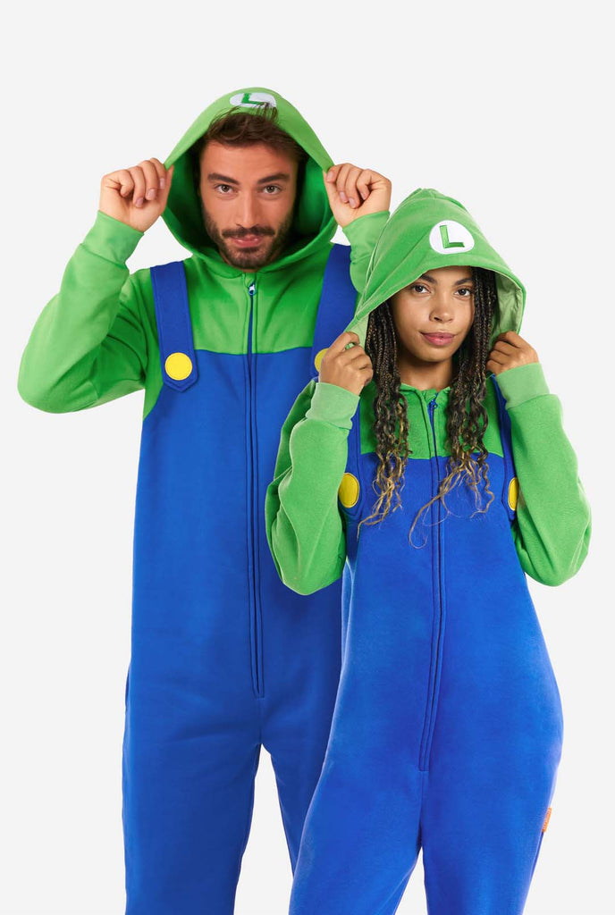 Ein Mann und eine Frau tragen einen Luigi-Einteiler. Das Outfit besteht aus einem hellgrünen Kapuzenpullover mit einem „L“-Symbol auf der Kapuze und einem blauen Overall mit großen gelben Knöpfen an den Trägern. Das Gesamtdesign imitiert das Aussehen der beliebten Videospielfigur Luigi mit kontrastierenden Grün- und Blautönen. Der Hintergrund ist schlicht und legt den Fokus auf das Kostüm.