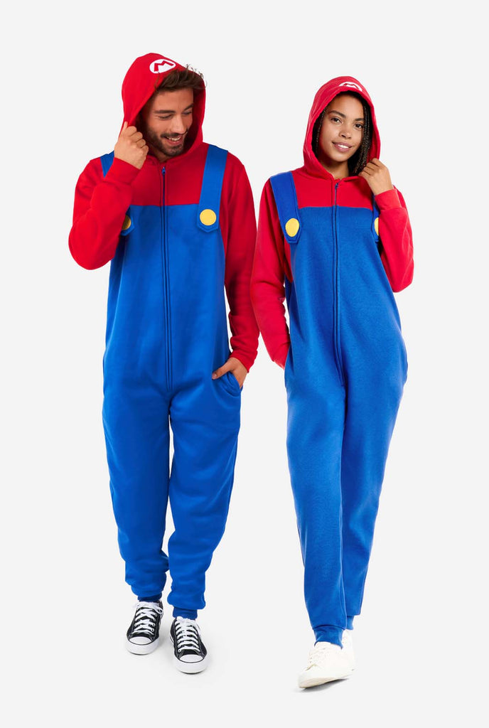 Mann und Frau tragen einen rot-blauen Unisex Onesie für Erwachsene mit Super-Mario-Motiv. Der Onesie ähnelt dem Super-Mario-Outfit.