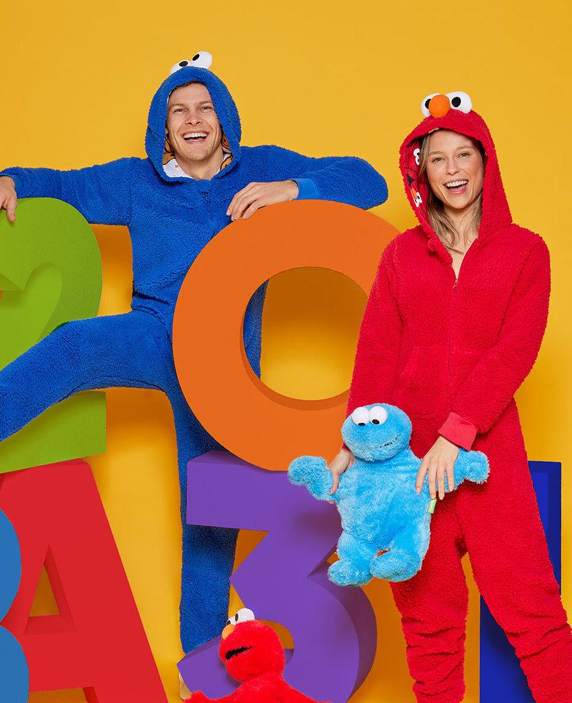 Mann trägt Krümelmonster-Onesie und Frau trägt Elmo-Onesie.